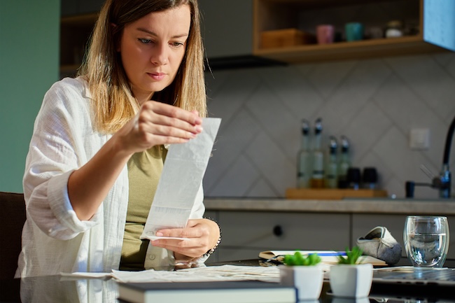 Woman analyzing financial bills and planning home budget in the kitchen